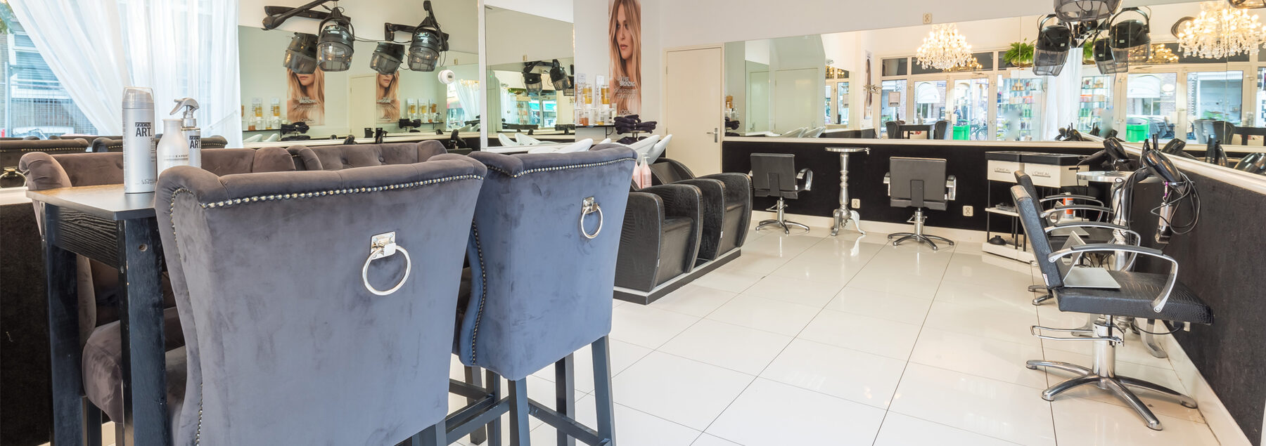 Het interieur van Ilona's Kapsalon met kappersstoelen, spiegels en L'Oréal-producten